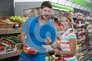 Couple Shopping At The Supermarket With Grocery List