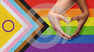 couple showing hand heart over progress pride flag photo