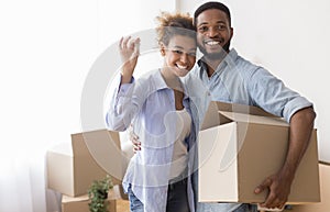 Couple Showing Key Holding Moving Box Standing In New Home