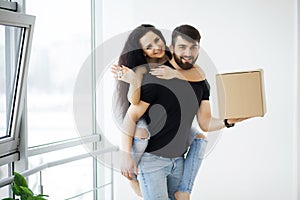 Couple showing keys to new home hugging looking at camera