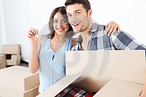 Couple showing keys to new home hugging looking at camera