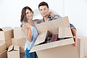 Couple showing keys to new home hugging looking at camera