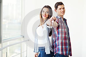 Couple showing keys to new home hugging, together unpacking card