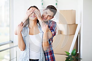 Couple showing keys to new home hugging, together unpacking card