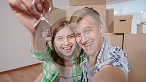 Couple showing keys to new home and selfie