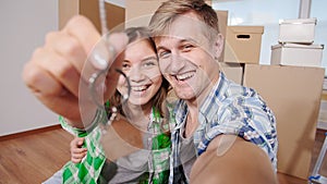 Couple showing keys to new home and selfie