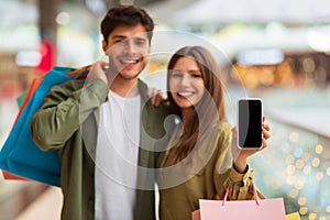 Couple Showing Phone Advertising Application For Mobile Shopping In Mall