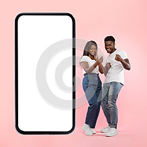 Couple showing white empty smartphone screen and making win gesture