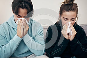 Couple, sick and couch with tissue, sickness and virus for infection, sinus and cold symptoms. Sneeze, blowing nose and