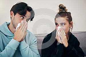 Couple, sick and virus with tissue, sofa and sickness for infection, sinus and cold symptoms. Sneeze, blowing nose and