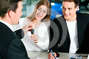 Couple signing sales contract at car dealer