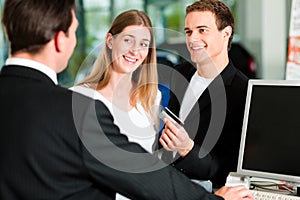 Couple signing sales contract at car dealer