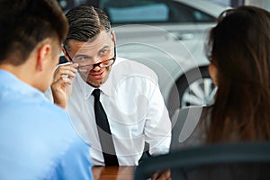 Couple Signing Salesman Contract. Car Showroom