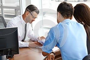 Couple Signing Salesman Contract. Car Showroom