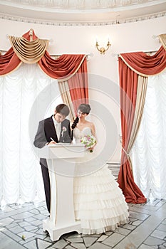 Bride and groom signing a wedding document photo