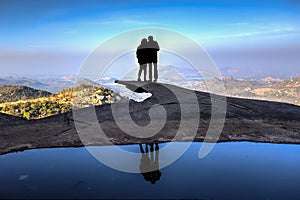 Couple silhouette on the edge of a cliff