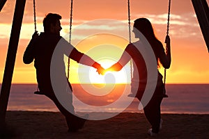Couple silhouette holding hands watching a sunrise
