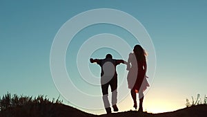 Couple silhouette running toward the sun outdoors at sunset dramatic sky background. young happy couple jumping on