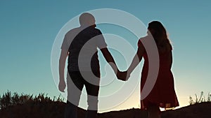 Couple silhouette walking holding hand toward the sun outdoors at sunset dramatic sky background. young happy couple go