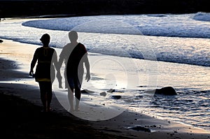 Couple silhouette walking at the seaside at sunset