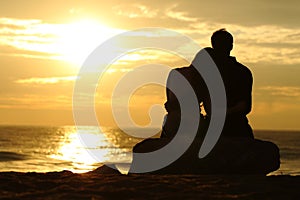 Couple silhouette watching sunset on the beach