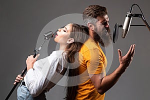 Couple singing. Singing man and girl in a recording studio. Expressive couple with microphone. Karaoke signer, musical
