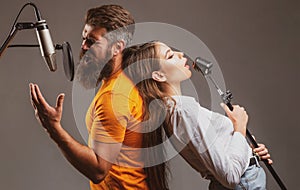 Couple singing. Singing man and girl in a recording studio. Expressive couple with microphone. Karaoke signer, musical