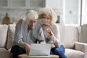 Couple sit on couch staring at laptop using ecommerce website