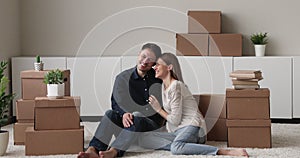Couple sit on floor resting at relocation day near boxes