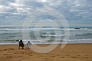 A couple siting on the beach Praia de Odeceixe in South Portugal