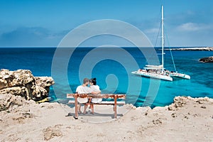 A couple sits on a bench and looks at the lagoon