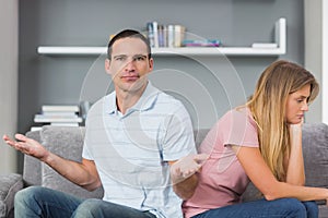 Couple sitting back to back after a fight on the couch with man