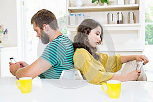 Couple sitting back to back and text messing on mobile phone