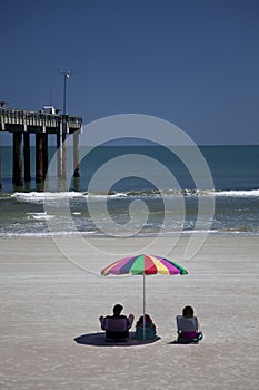 Couple Sitting on Beach with Beach Umbrella