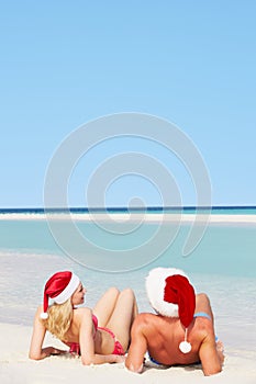 Couple Sitting On Beach Wearing Santa Hats