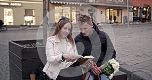 Couple sitting on bech and reading a book