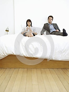 Couple Sitting On Bed, Ignoring
