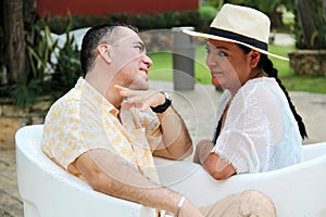 Couple sitting on a bench confidant chairs in Merida in Yucatan Mexico show their love with flirtatious looks and kisses