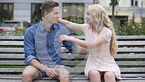 Couple sitting on bench after having fight, making up and kissing, relationship
