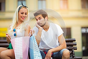 Couple sitting on a bench and holding shopping bags