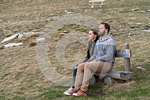 Couple sitting on bench and looking at mountains