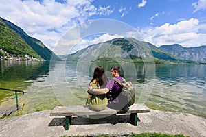 Couple sitting on bench over Austrian alps lake in Hallstatt, Salzkammergut, Austria