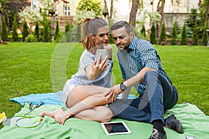 Couple sitting on the blaket, spending nice time and taking self