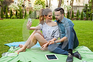 Couple sitting on the blaket, spending nice time and taking self