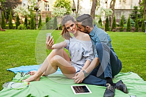 Couple sitting on the blaket, spending nice time and taking self