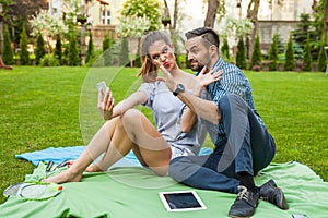 Couple sitting on the blaket, spending nice time and taking self