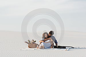 Couple sitting on blanket with basket of fruits and acoustic guitar on beach
