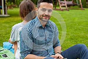 Couple sitting on the blanket and the gorl is using phone