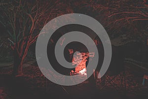 Couple sitting at burning camp fire in the night. Camping in the forest under starry sky, Namibia, Africa. Summer adventures and