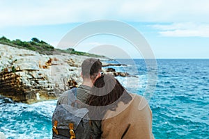 couple sitting on the cliff looking at sea